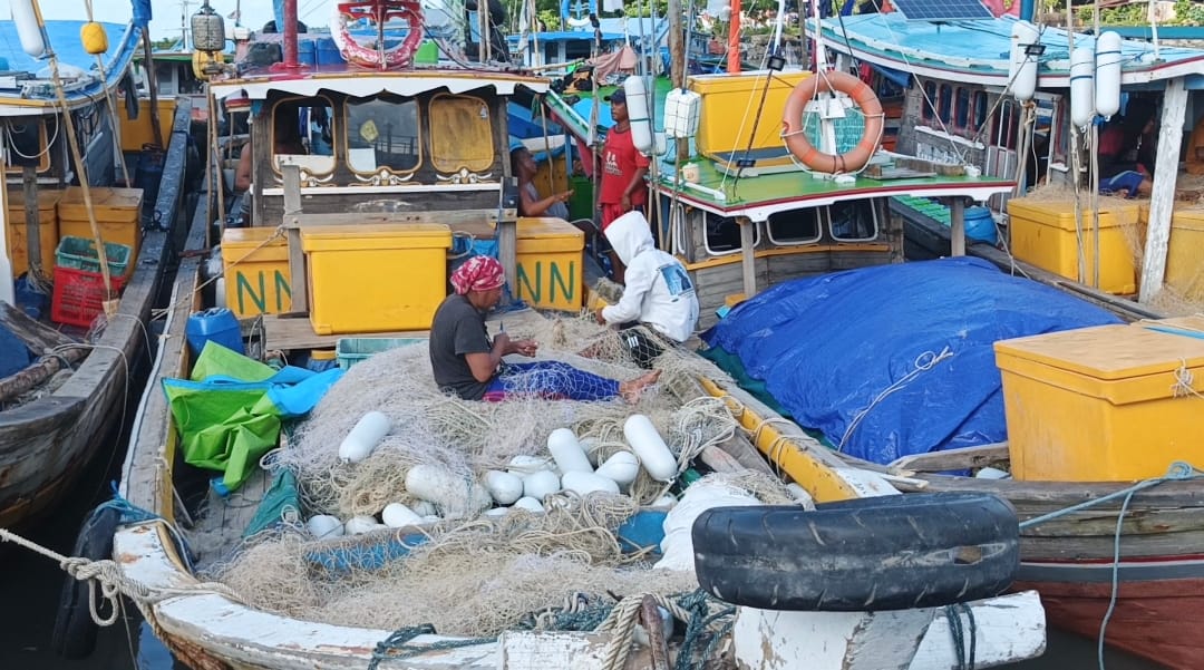 Caption : Para nelayan sedang memperbaiki pukat (jaring penangkapan ikan) saat kapal bersandar di pelabuhan ikan Mentok, Selasa (10/12/2024). (Sorotanbangka.com).